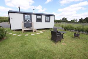 a tiny house with a table and chairs in a yard at Springwood Shepherd Huts Glamping York in York