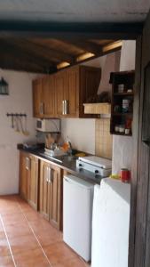 Una cocina con gabinetes de madera y un refrigerador blanco. en Casa Cueva Manuel y María, en El Juncal