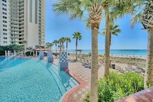a swimming pool next to a beach with palm trees at Deluxe Beachfront Studio, Shores of Panama New and Renovated in Panama City Beach