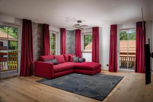 un soggiorno con divano rosso di fronte alle finestre di Luxury Apartments "R6 Tegernsee" a Bad Wiessee