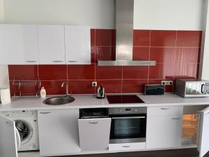 a small kitchen with white cabinets and red tiles at Apartamentai Fortuna in Kaunas
