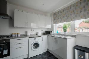 a kitchen with white cabinets and a washer and dryer at Hullidays - The Auckland House University Quarter in Hull