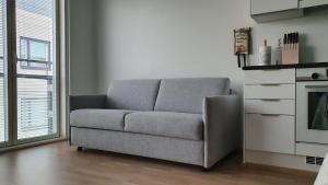 un sofá sentado en una sala de estar junto a una ventana en Parvekkeellinen yksiö keskustassa en Turku