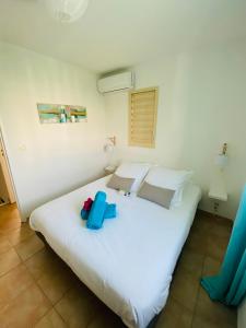 - une chambre dotée d'un grand lit blanc avec des éléments bleus dans l'établissement Maison mitoyenne , piscine,Citerne, jardin, parking, plage, au Gosier