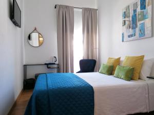 a bedroom with a bed with a blue blanket and a window at Guia Guest House in São Bartolomeu de Messines