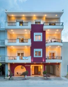 a large purple building with potted plants in front of it at Niovi Luxury Apartments in Loutra Edipsou