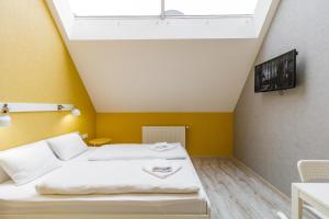 a bedroom with a white bed and a yellow wall at Opera Passage Hotel & Apartments in Lviv