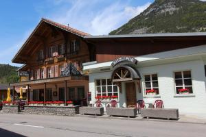 a building with red chairs in front of it at Hotel-Restaurant Alpina in Innertkirchen