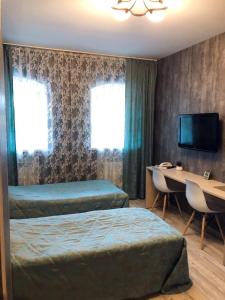 キーロフにあるInn Na Pristanskoyのベッド2台、デスク、テレビが備わるホテルルームです。