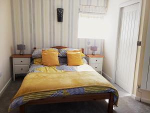 1 dormitorio con 1 cama con almohadas amarillas en Hartpury B&B, en Hartpury