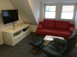 sala de estar con sofá rojo y TV en Ferienwohnung „Im Kleinen Löök“ - DG - 2 Zimmer - Balkon - Boxspringbett - 2 TV, en Rinteln