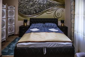 a bedroom with a bed with a large headboard at Villa Apartman in Makó