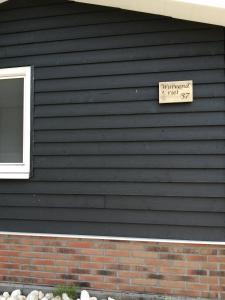 a black house with a sign on the side of it at Wuivend Riet gelegen op Resort Venetie in Giethoorn
