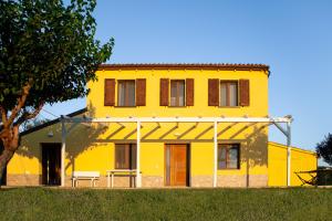 Una casa amarilla con un árbol delante. en La Casa Del Sole en Gradara