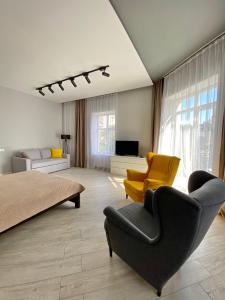 a living room with a bed and a couch and chairs at Serbska Apartment in Lviv