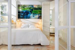 Un dormitorio con una cama blanca y un cuadro en la pared. en UNICO ALCAZAR Apartment, en Sevilla