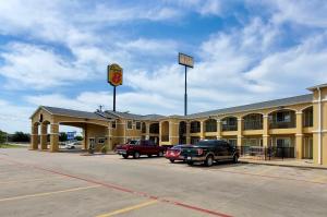 a hotel with cars parked in a parking lot at Super 8 by Wyndham Forney/East Dallas in Forney