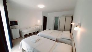 a white room with two beds and a mirror at Vila Tropicana in Eforie Sud