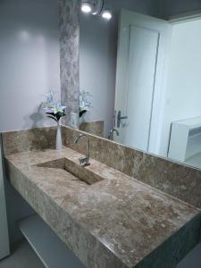 a bathroom with a marble sink with a mirror at Guest House Forno in Búzios