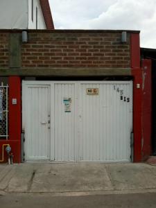 dos puertas blancas de garaje en un edificio de ladrillo en Hostal Maple, en Querétaro