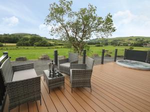 a wooden deck with wicker chairs and a table at Hazel Lodge in Llanidloes