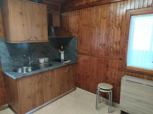 kuchnia z drewnianymi szafkami, zlewem i stołkiem w obiekcie Casas da Chousa w mieście Roupar