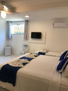 a bedroom with two beds and a flat screen tv at Guest House Forno in Búzios