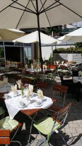 un restaurante con mesas, sillas y sombrilla en Stadthotel Deggendorf en Deggendorf