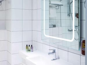 baño blanco con ducha y lavamanos en Mercure Telford Centre Hotel en Telford