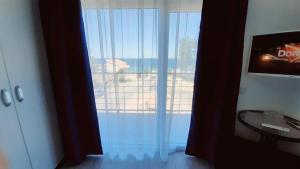 um quarto com uma grande porta de vidro com uma janela em Vila Tropicana em Eforie Sud