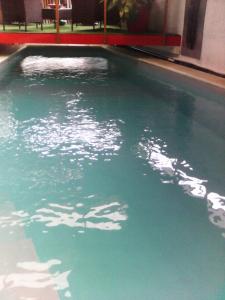 a swimming pool with green water in a building at Alain in Noumea