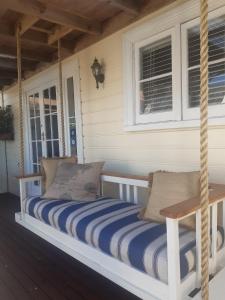 eine Hollywoodschaukel auf der Veranda eines Hauses in der Unterkunft Harbour View Cottage in Auckland