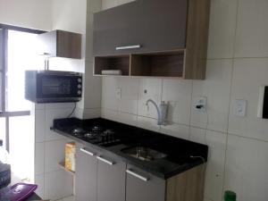 uma pequena cozinha com fogão e micro-ondas em Flat Ana Regis ap1010 em Salvador