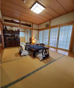 una sala de estar con mesa en una habitación con ventanas en サムライストリートハウス武家屋敷通り, en Daisen