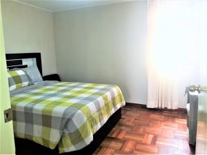 a bedroom with a bed with a checkered blanket at Royalty Inn in Lima