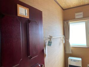 ein Bad mit einer Tür, einem Fenster und einem Fenster in der Unterkunft Guest House Nemuroman in Nemuro