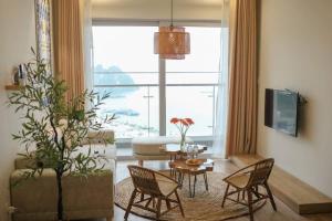 a living room with a table and chairs and a large window at BOM HOMES- THE SAPPHIRE HA LONG RESIDENCE APARTMENt in Ha Long