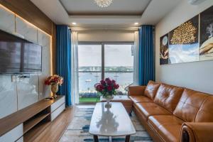 a living room with a leather couch and a table at BOM HOMES- THE SAPPHIRE HA LONG RESIDENCE APARTMENt in Ha Long