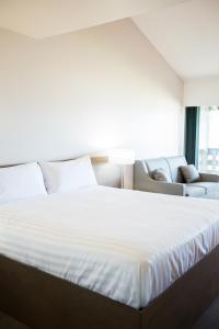 a bedroom with a large white bed and a couch at Sand Pebbles Inn in Qualicum Beach