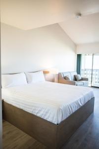 1 dormitorio con 1 cama blanca grande y 1 sofá en Sand Pebbles Inn, en Qualicum Beach