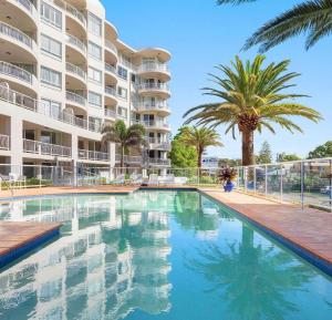 a swimming pool in front of a large apartment building at Kirra Beach Apartments in Gold Coast