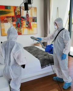 two people in protective suits washing a bed at Villa Anar in Bophut 