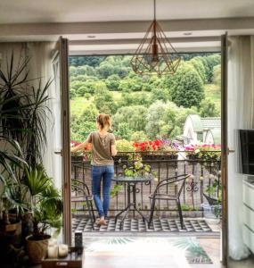 a woman walking on a balcony looking out the door at Apartament Dobre Miejsce in Ustrzyki Dolne