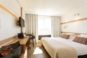 ein Hotelzimmer mit zwei Betten, einem Schreibtisch und einem Fernseher in der Unterkunft The Originals Boutique, Hôtel Neptune, Montpellier Sud in Carnon-Plage