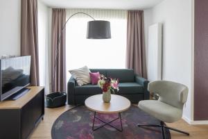 ein Wohnzimmer mit einem Sofa, einem Stuhl und einem Tisch in der Unterkunft Hotel Upstalsboom Langeoog in Langeoog