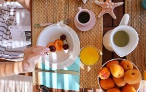 a person holding a bowl of fruit and a cup of coffee at Elefthia Syros Exclusive Suite in Megas Yialos-Nites