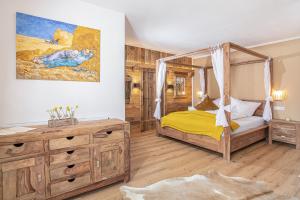 ein Schlafzimmer mit einem Himmelbett und einer Holzkommode in der Unterkunft Gasthof Dorfwirt Sandgruber Ges.m.b.H in Pertisau