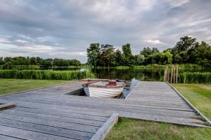 a wooden dock with a boat on the water at The Lily Pad in Thorpeness