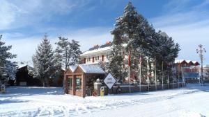 ein kleines Gebäude im Schnee vor einem Gebäude in der Unterkunft Hotel Aşıkoğlu in Bogazkale