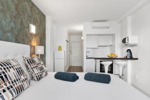 a white bedroom with a large white bed and a kitchen at Estudios Bahia in Illetas